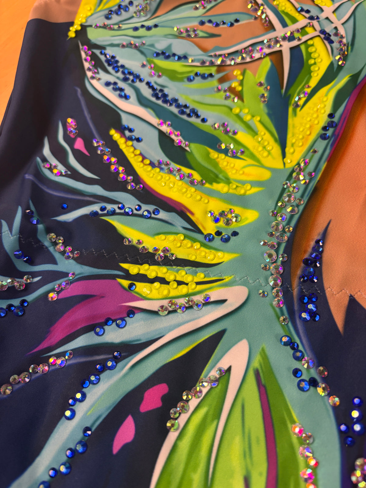 Détail de Dalí avec des pierres bleues et transparentes sur l’imprimé turquoise, vert citron et blanc.