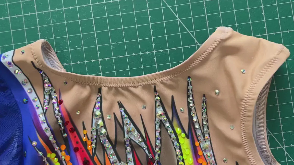 Détail de l’encolure Dexa : lignes de strass sur fond nude avec traits bleus, jaunes, roses et orange.