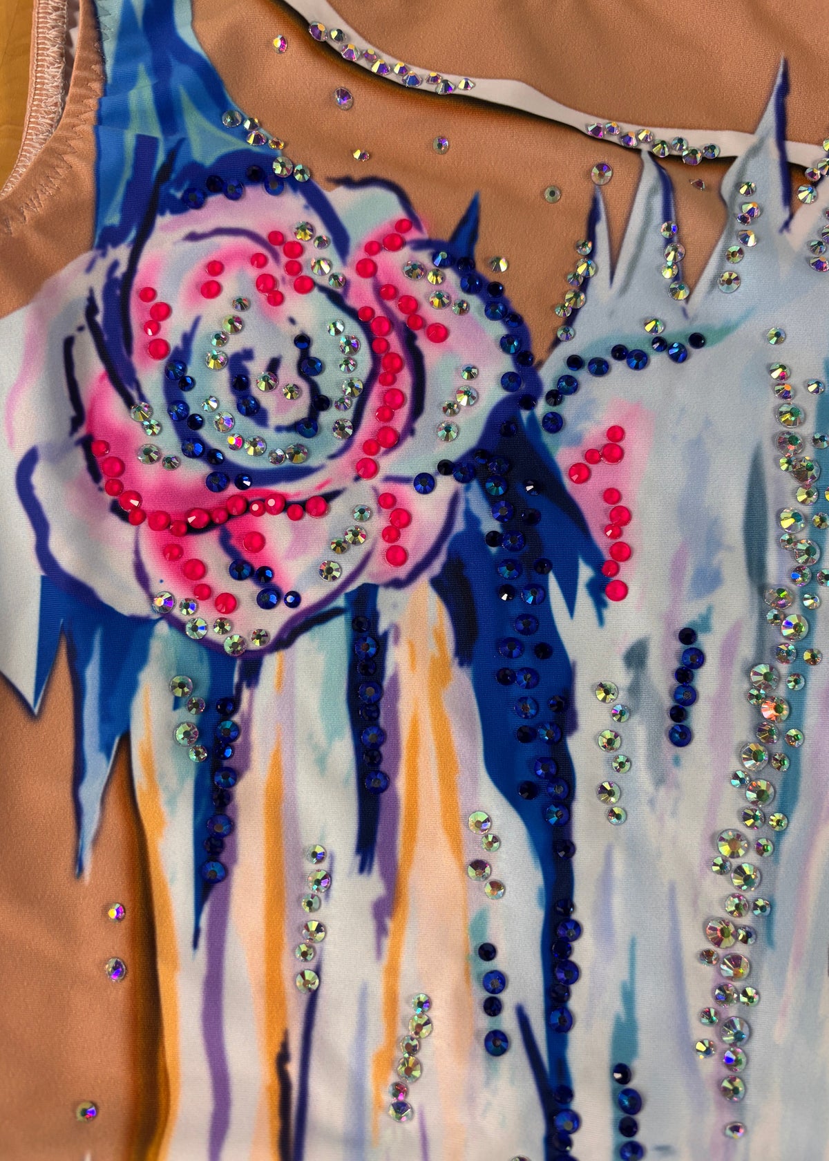 Détail de la fleur rose et bleue et des ornements bleus, roses et irisés près de l’encolure.