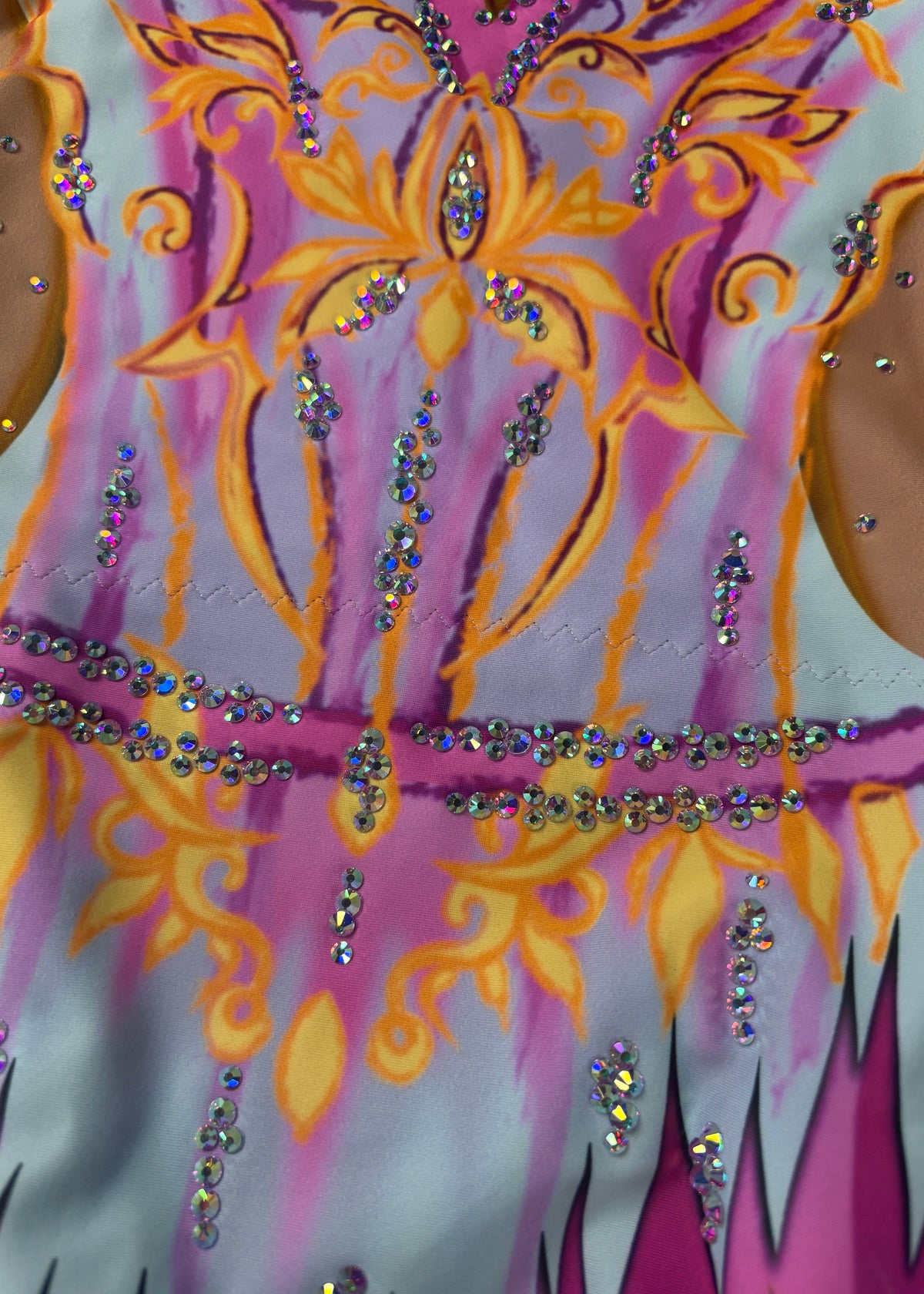 Détail de l’ornement jaune et orange et des lignes de cristaux sur fond bleu ciel et rose.