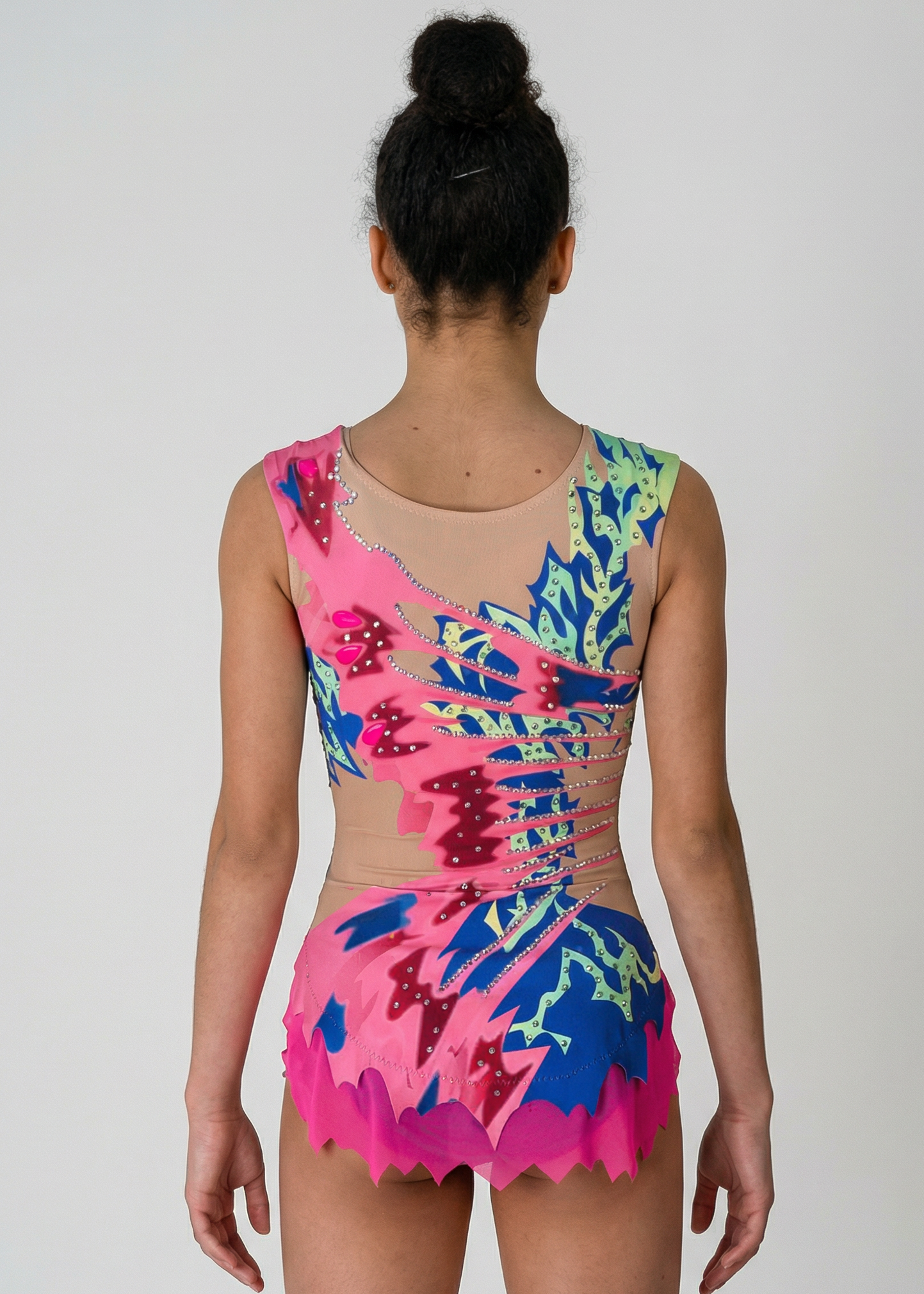 Maillot de gimnasia rítmica en rosa, azul y verde con pedrería, transparencias simuladas laterales y motivos dinámicos creando un estilo vibrante.
Maillot de gimnasia rítmica color claro con rosas intensos, azules y verdes, pedrería brillante y diseño asimétrico de apariencia energética.
Maillot de gimnasia rítmica visto por la espalda en base clara con rosas, azules y verdes, pedrería y motivos fluidos de estilo dinámico.