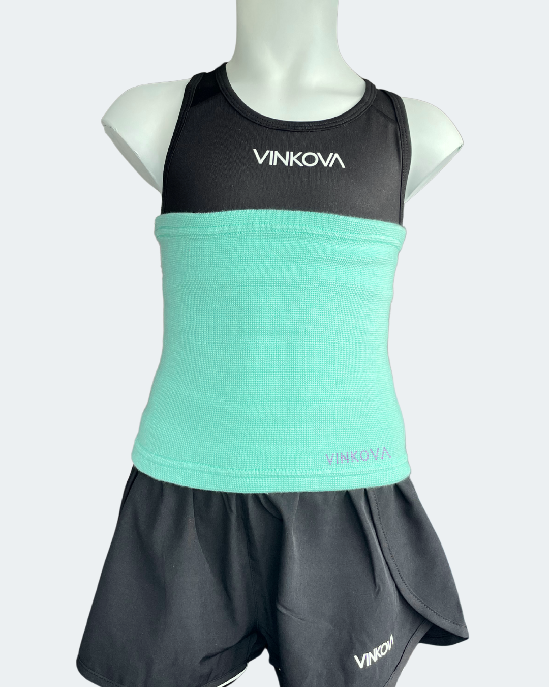 Vinkova waist warmer, colour: turquoise, on a mannequin wearing a black outfit.