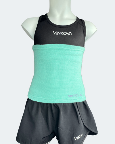 Vinkova waist warmer, colour: turquoise, on a mannequin wearing a black outfit.