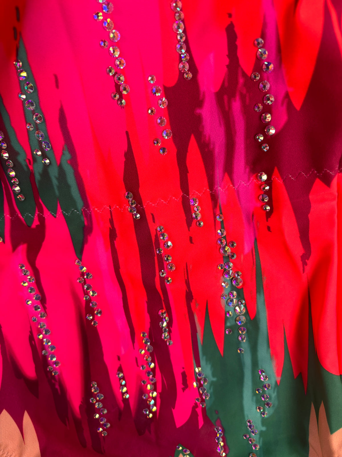 Gros plan de Matisse avec lignes de pierres brillantes sur des formes fuchsia, rouges et vert foncé.