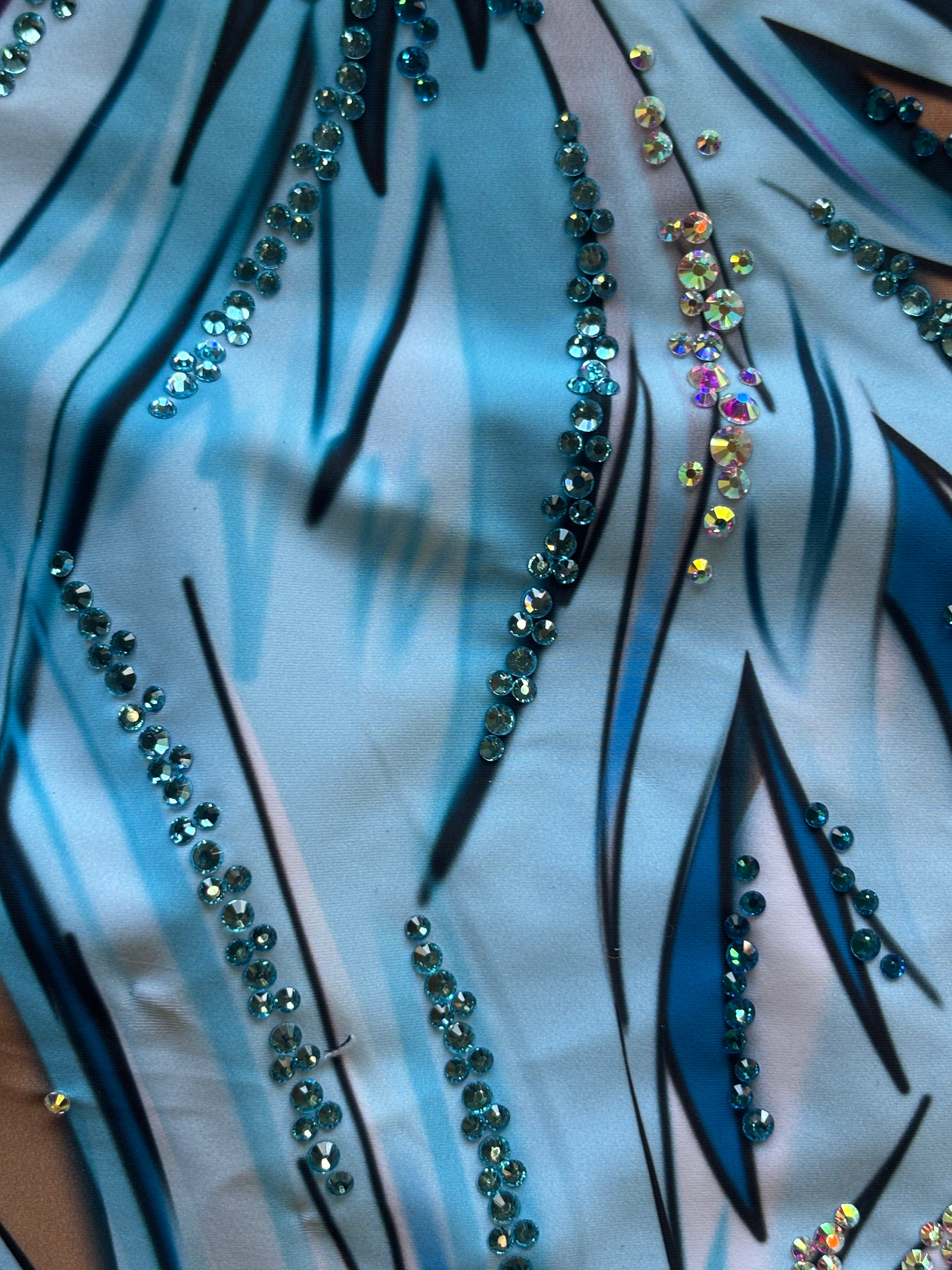 Maillot profesional de gimnasia rítmica con mangas asimétricas en tonos azules y efecto pluma.