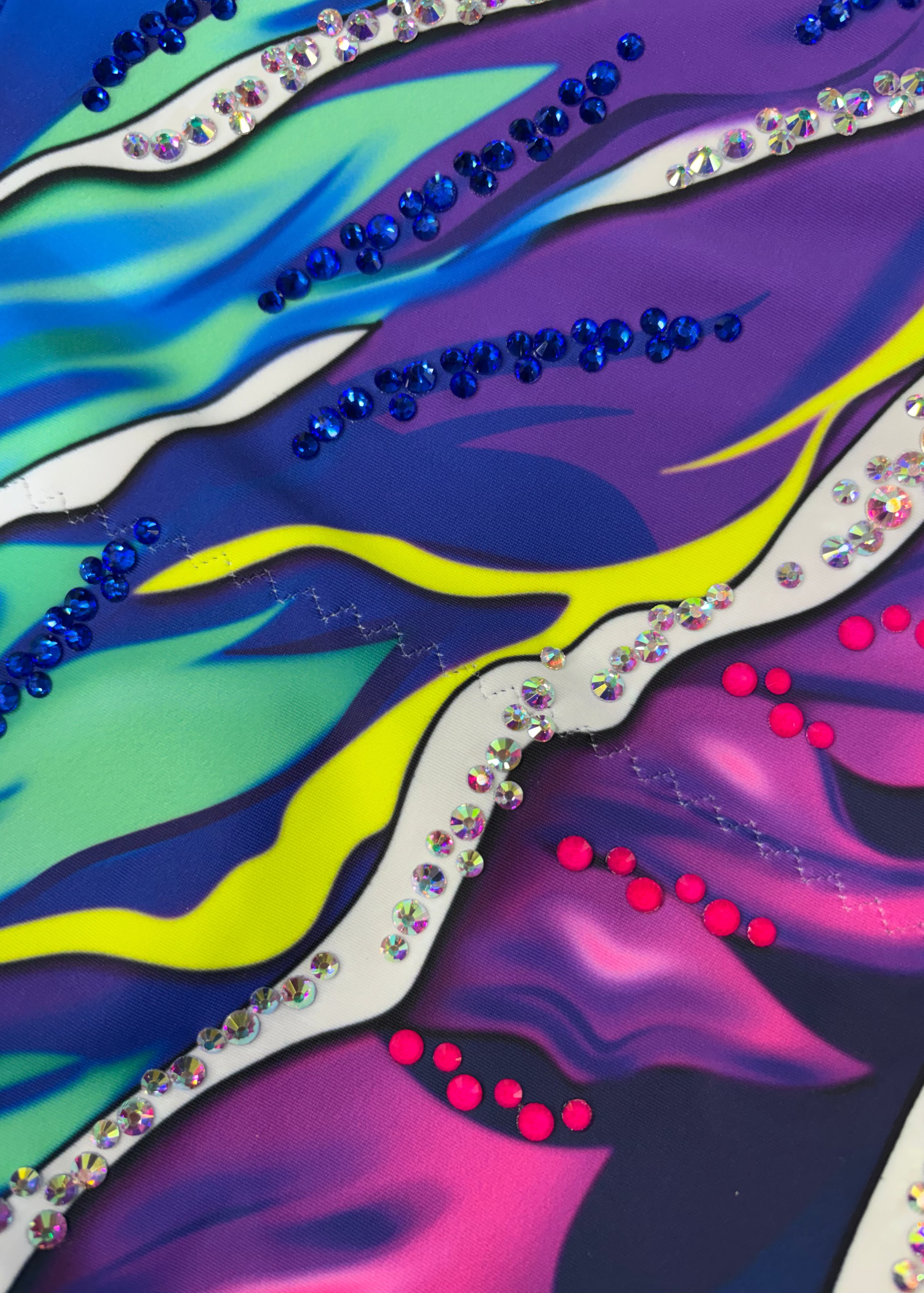 Maillot de competición con malla carne, pedrería brillante y diseño artístico multicolor elástico.